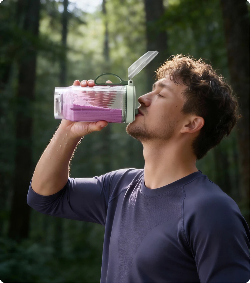 Usuario bebiendo un batido del vaso portátil Dreame Portable Blender durante una caminata por el bosque